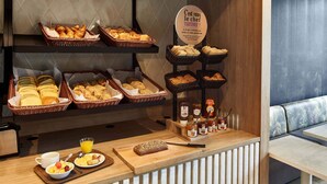 Un buffet de petit-déjeuner comprenant du pain, des viennoiseries et diverses garnitures.