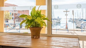 A potted plant on a wooden table by a window with a marina view. - B&B HOTEL Martigues Port-de-Bouc (Port-de-Bouc)