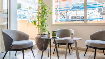 A seating area with two grey armchairs and a small table, a potted plant, and a sign on the table.
