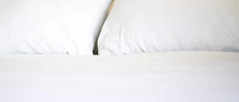 A bed with white bedding and pillows.
