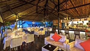 Un comedor interior con mesas y sillas, una barra y una estatua grande.