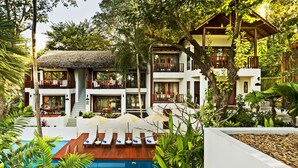 Un complejo turístico con piscina, varios balcones y abundante vegetación.