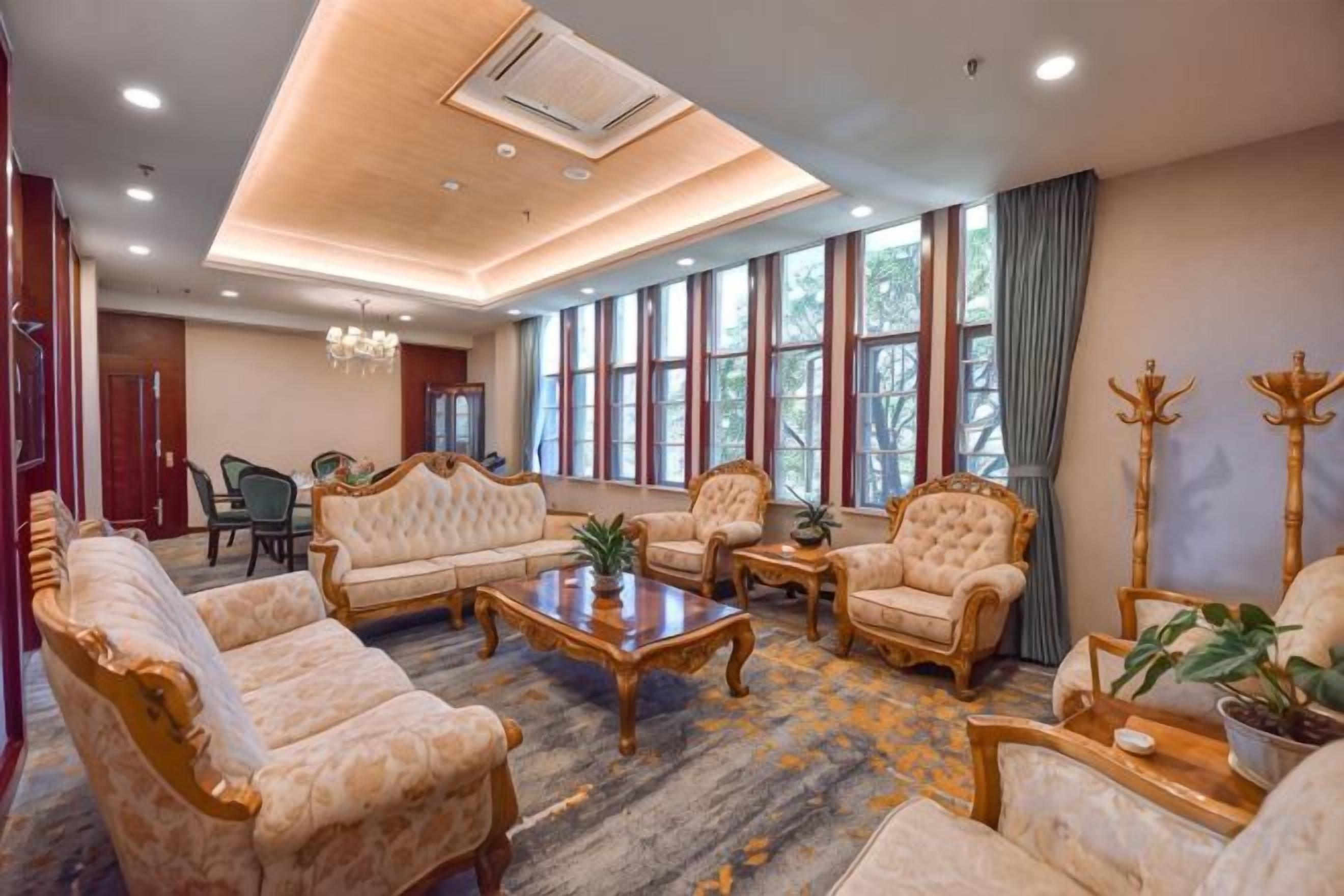A spacious living room with a sofa set, armchairs, a coffee table, and a chandelier.