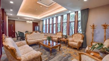 A spacious living room with a sofa set, armchairs, a coffee table, and a chandelier.