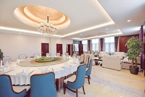 A conference room with a round table, blue chairs, a chandelier, and a potted plant. - Yuntian Garden Hotel (Kunming)