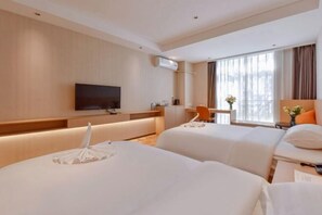 A hotel room with two beds, a desk, a chair, a TV, and a window with curtains.