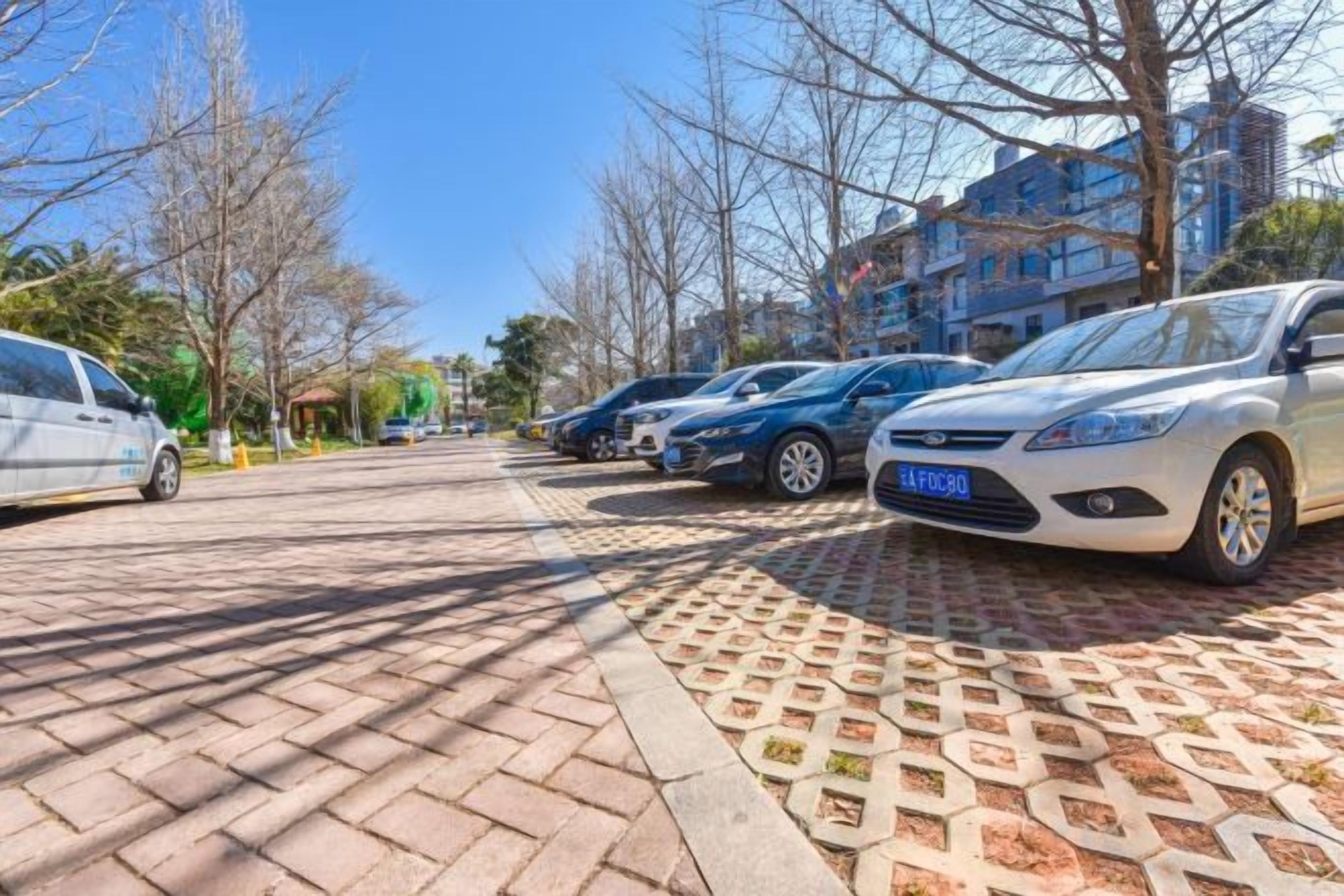 A parking area with multiple cars, a clear sky, and buildings in the background.
