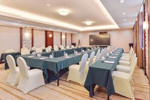 A conference room with long tables, chairs, and a large screen. - Yuntian Garden Hotel (Kunming)