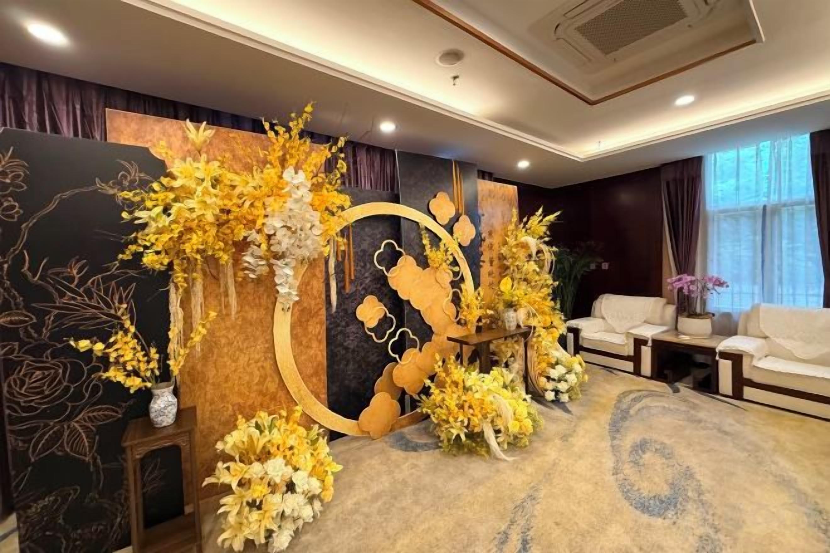 A room with a floral arrangement, a sofa, and a decorative wall piece.