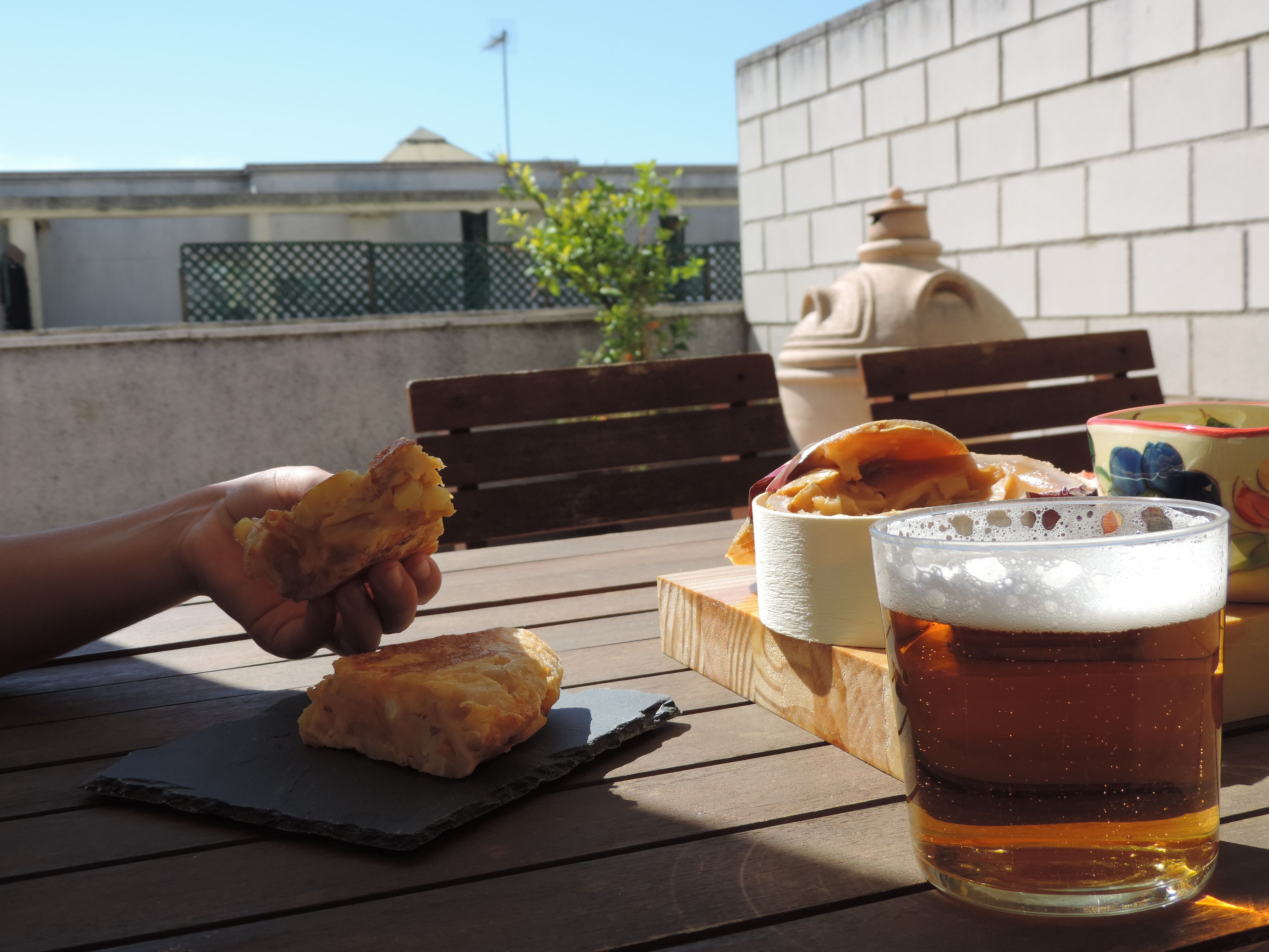 Comida con un trozo de pan y un plato en una mesa de madera. También se ve una jarra de cerveza.