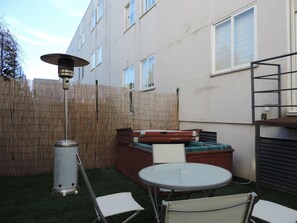 Un patio con una mesa redonda, dos sillas, un banco acolchado y un farol alto.