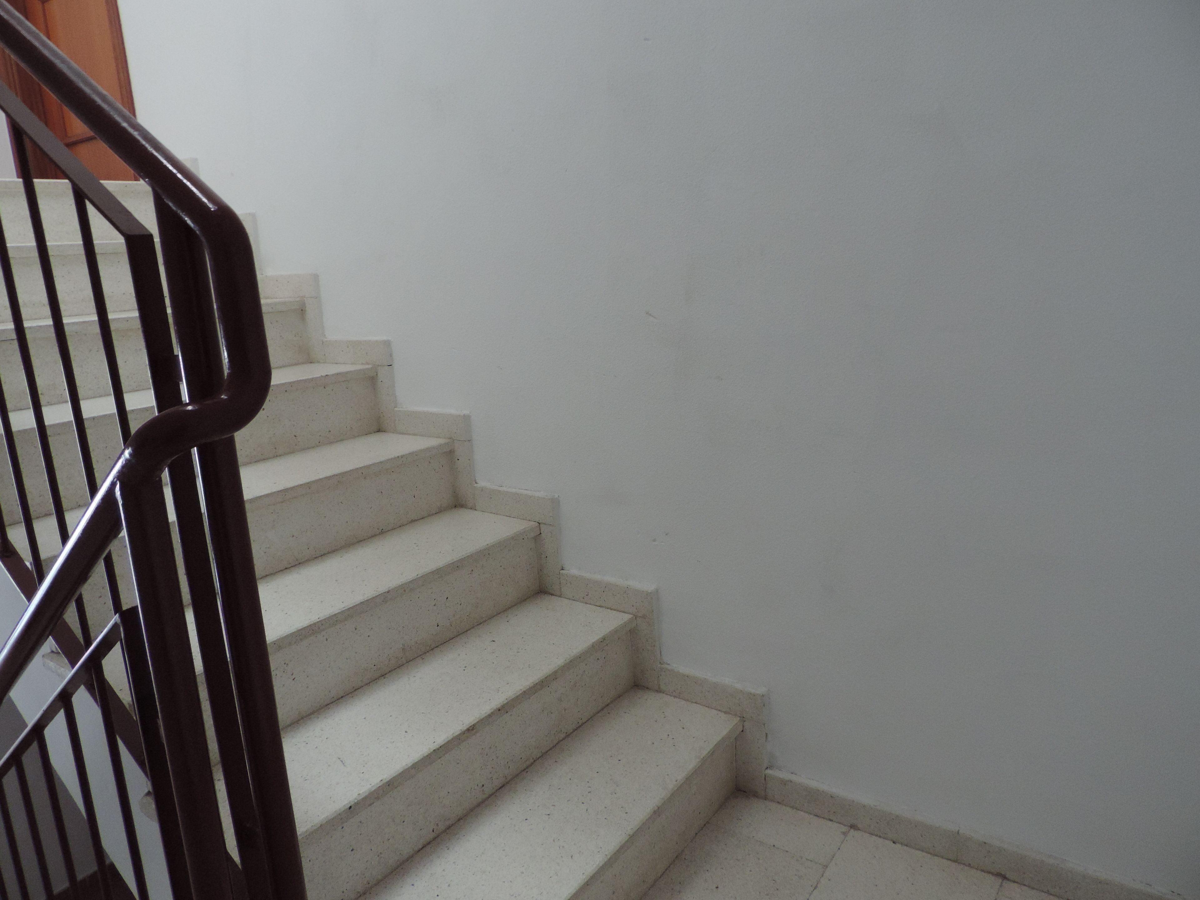 Una escalera con barandilla y pared blanca.