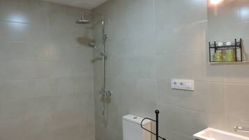 Une salle de bain avec douche, toilettes et lavabo.