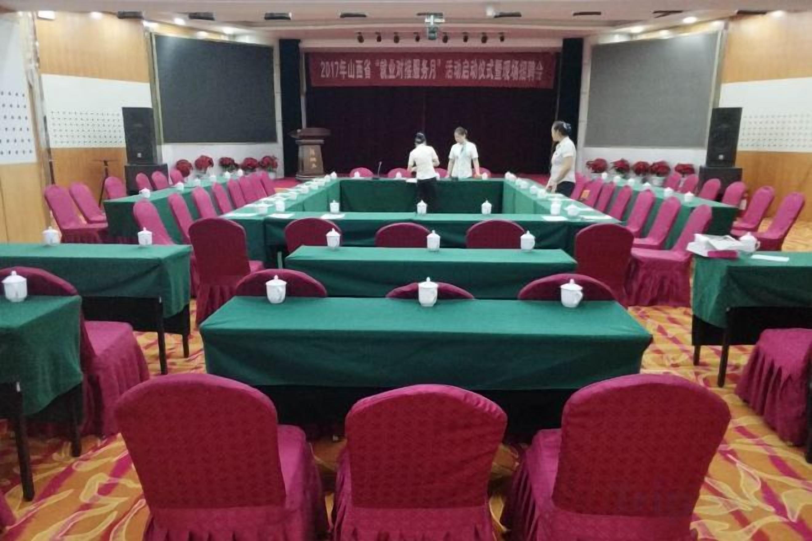 A conference room with tables and chairs, a podium, and a stage with a screen.