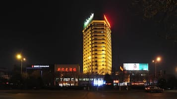 Un edificio a più piani con insegne illuminate, un ingresso ben visibile e un attraversamento pedonale in primo piano.