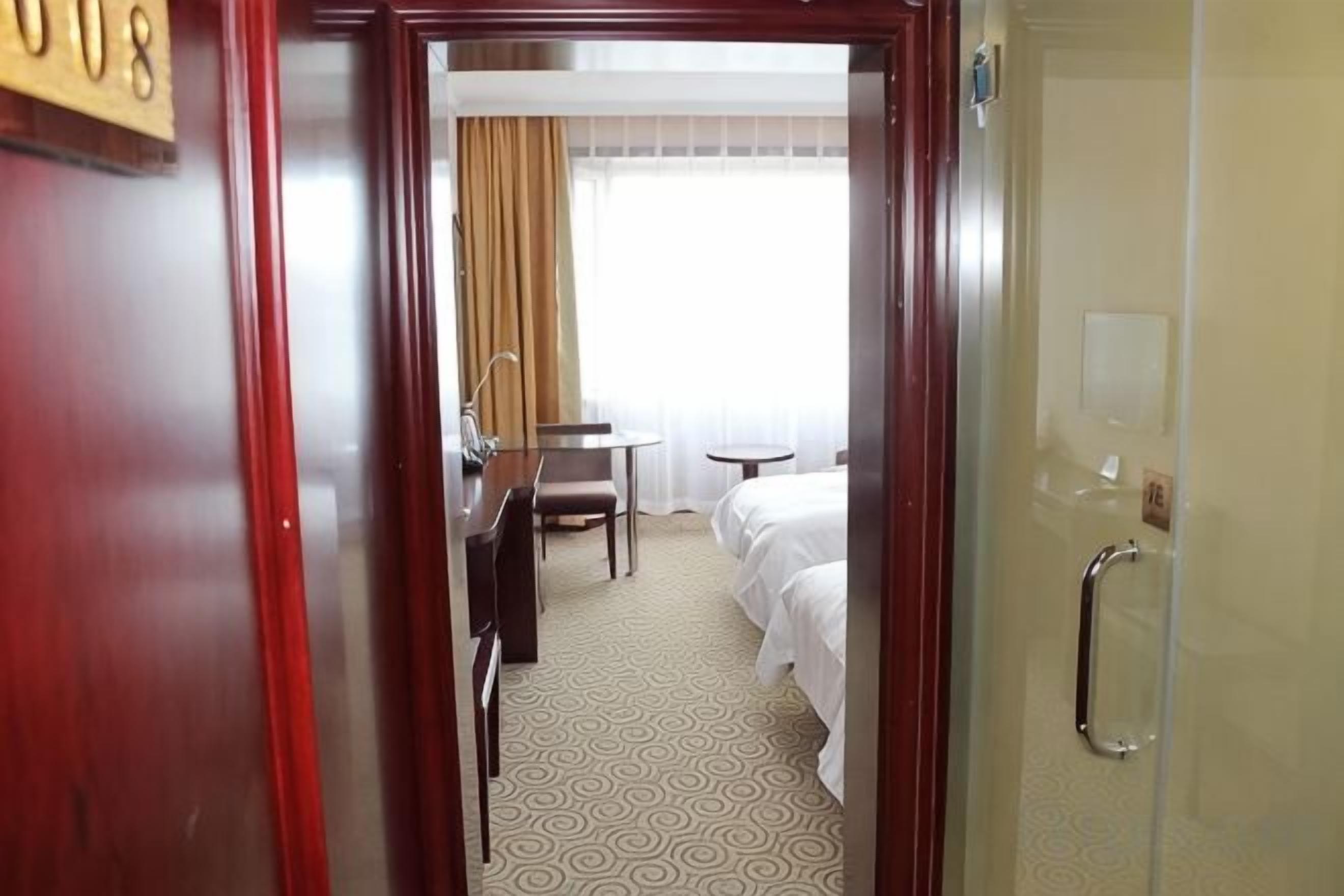 A hotel room with a bed, a desk, a chair, and a bathroom.