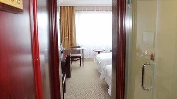 A hotel room with a bed, a desk, a chair, and a bathroom.