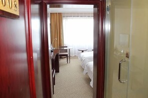 A hotel room with a bed, a desk, a chair, and a bathroom. - New Era Hotel (Shanxi Provincial Government) (Taiyuan)