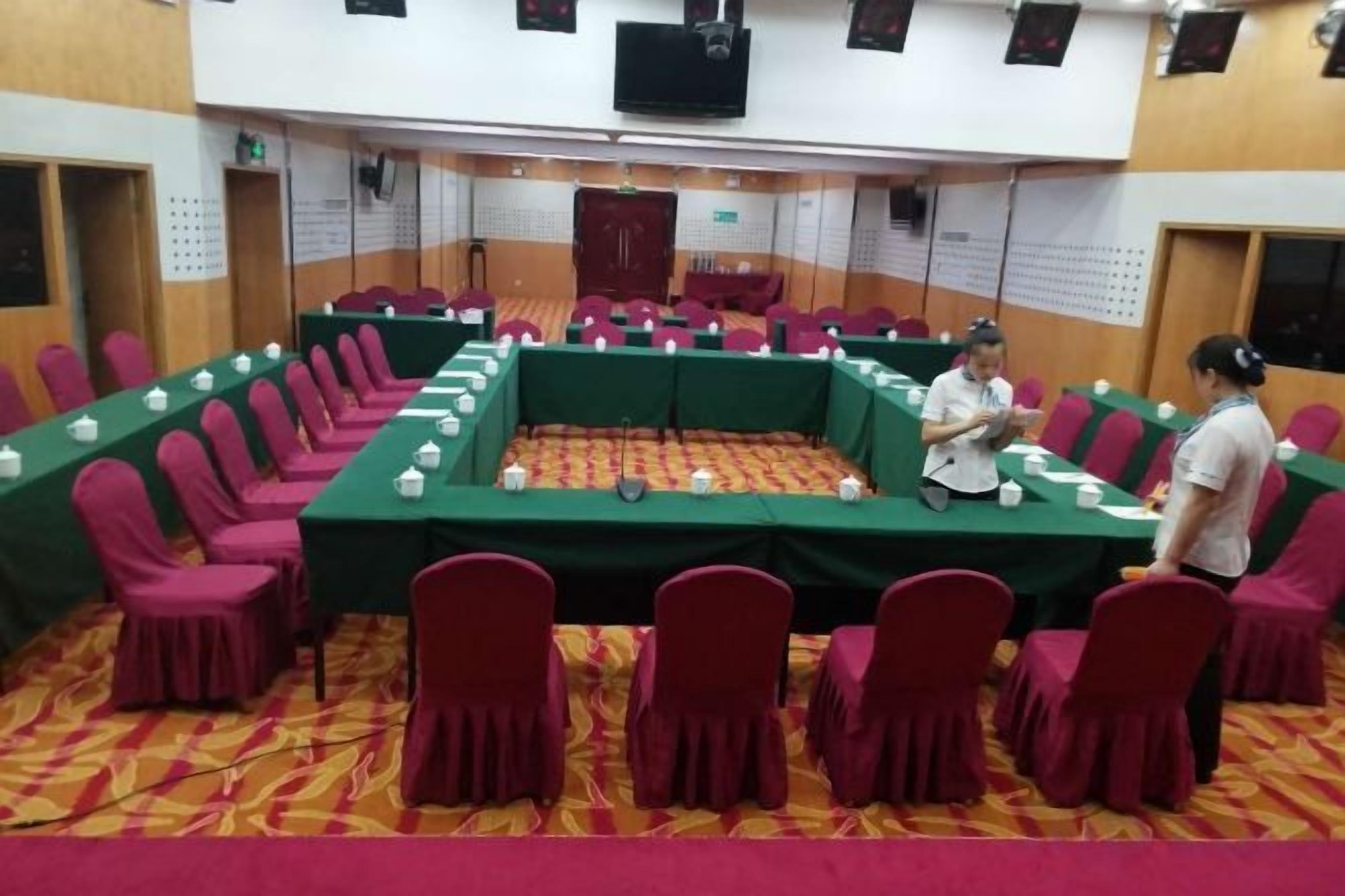 A conference room with a long table, chairs, and a person standing.