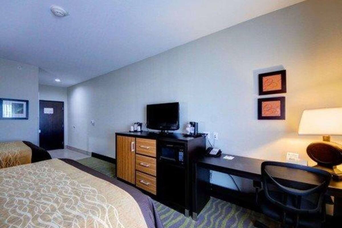 A hotel room with a bed, a desk with a computer, a television, and a chair.