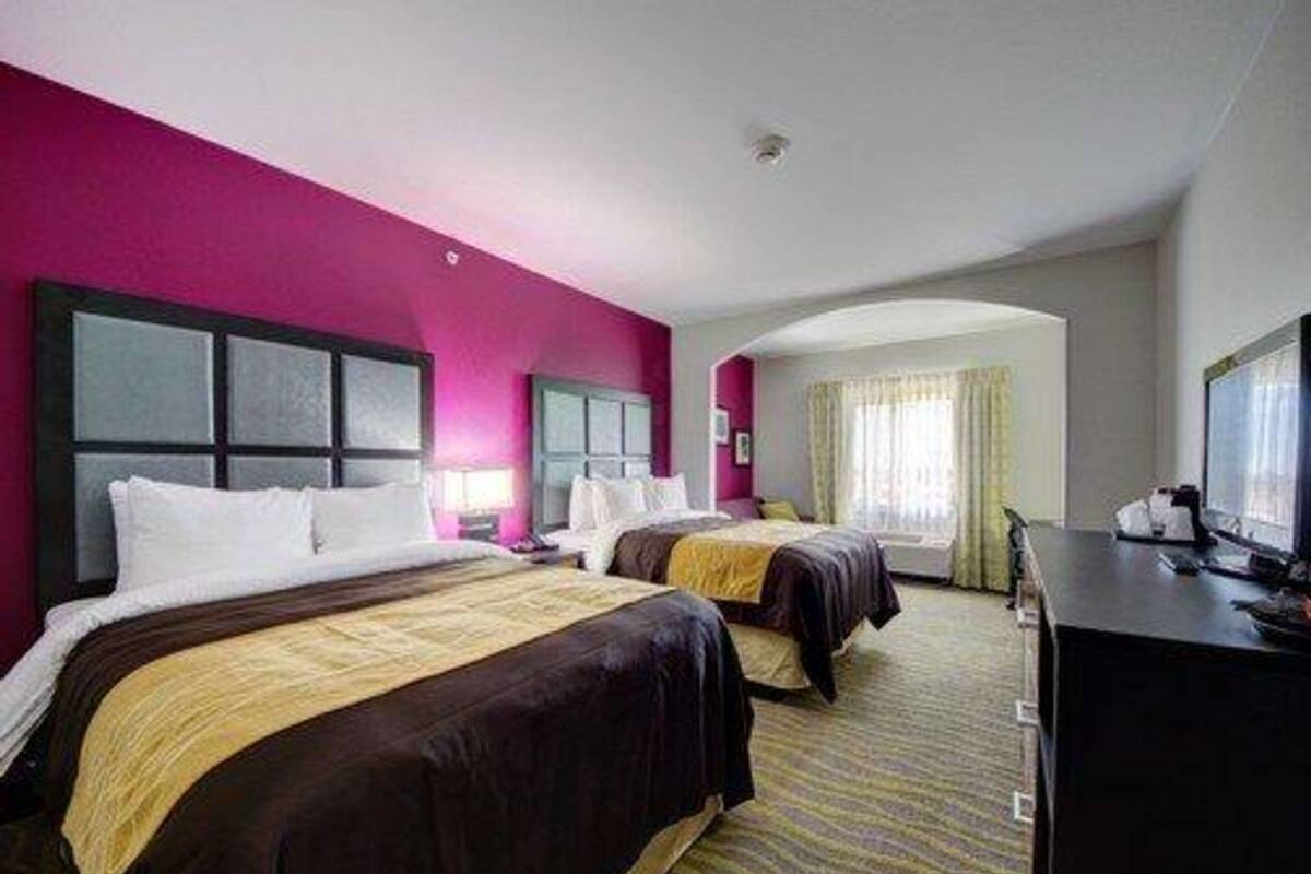 A hotel room with two beds, a desk, and a television.