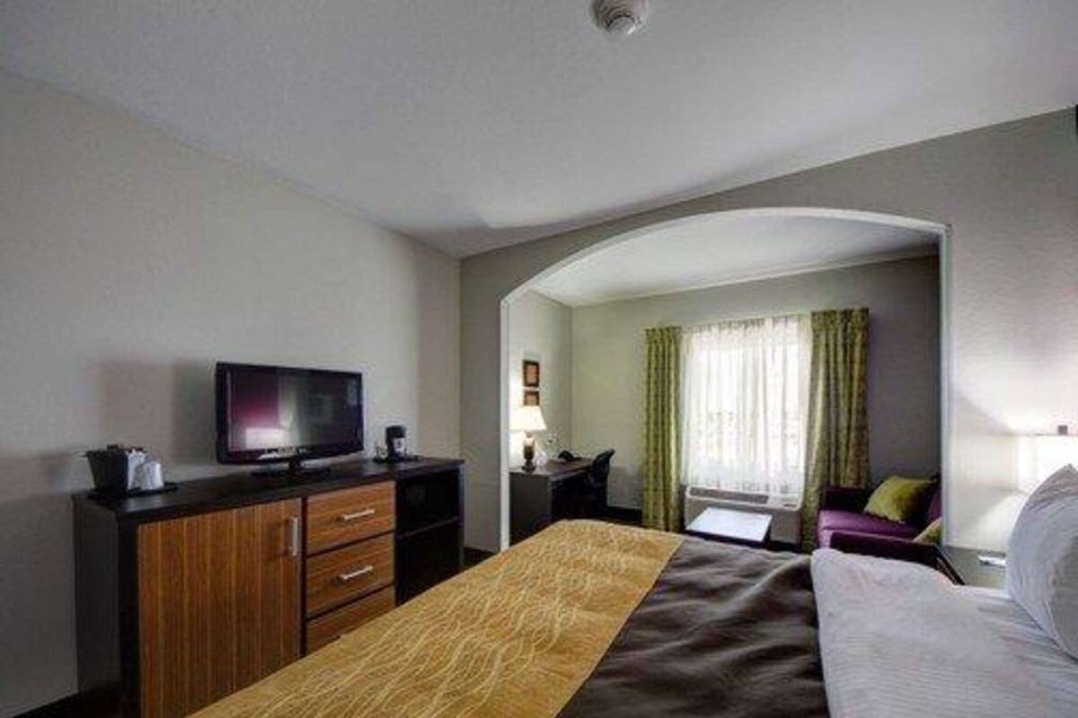 A hotel room with a bed, a desk, a television, and a window with curtains.