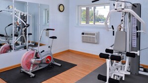 A gym with exercise equipment, a large mirror, and a window with a view of the outdoors.