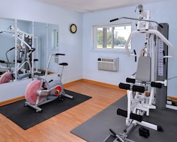 Uma academia com equipamentos de exercício, um espelho grande e uma janela com vista para o exterior.