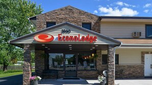A hotel entrance with a stone facade, a clear sky, and a parking lot.