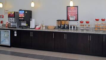 Un espace réservé au petit-déjeuner, équipé d’une machine à café, d’un grille-pain et où divers aliments sont présentés.