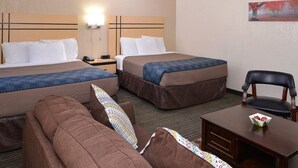 A hotel room with two beds, a sofa, a desk with a chair, and a painting on the wall.