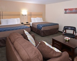 Quarto de hotel com duas camas, um sofá, uma escrivaninha com cadeira e um quadro na parede.