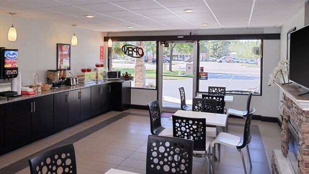 A restaurant with a counter, seating area, and a TV screen.