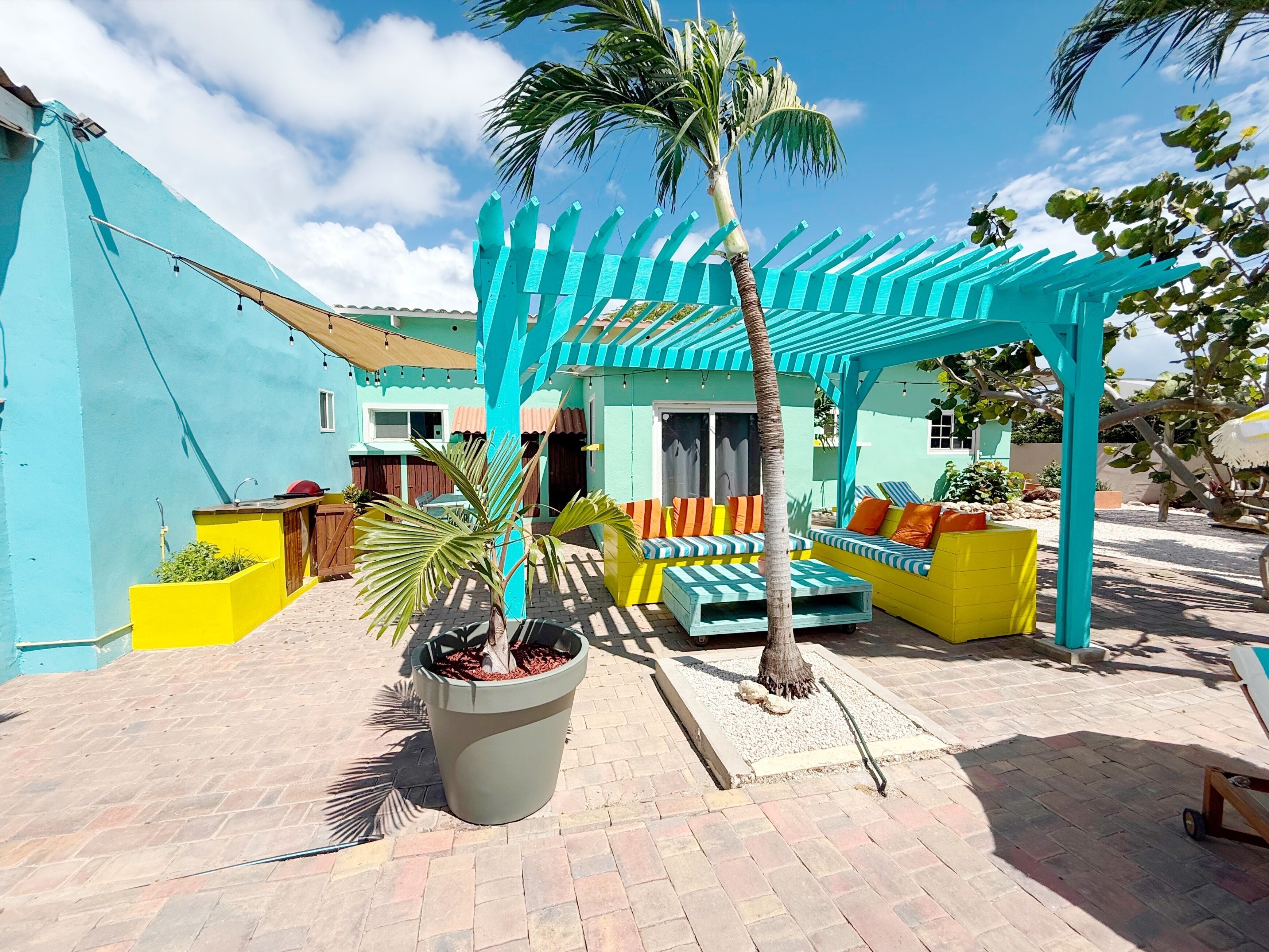 Un patio al aire libre vibrante con un colorido mobiliario y una pérgola.