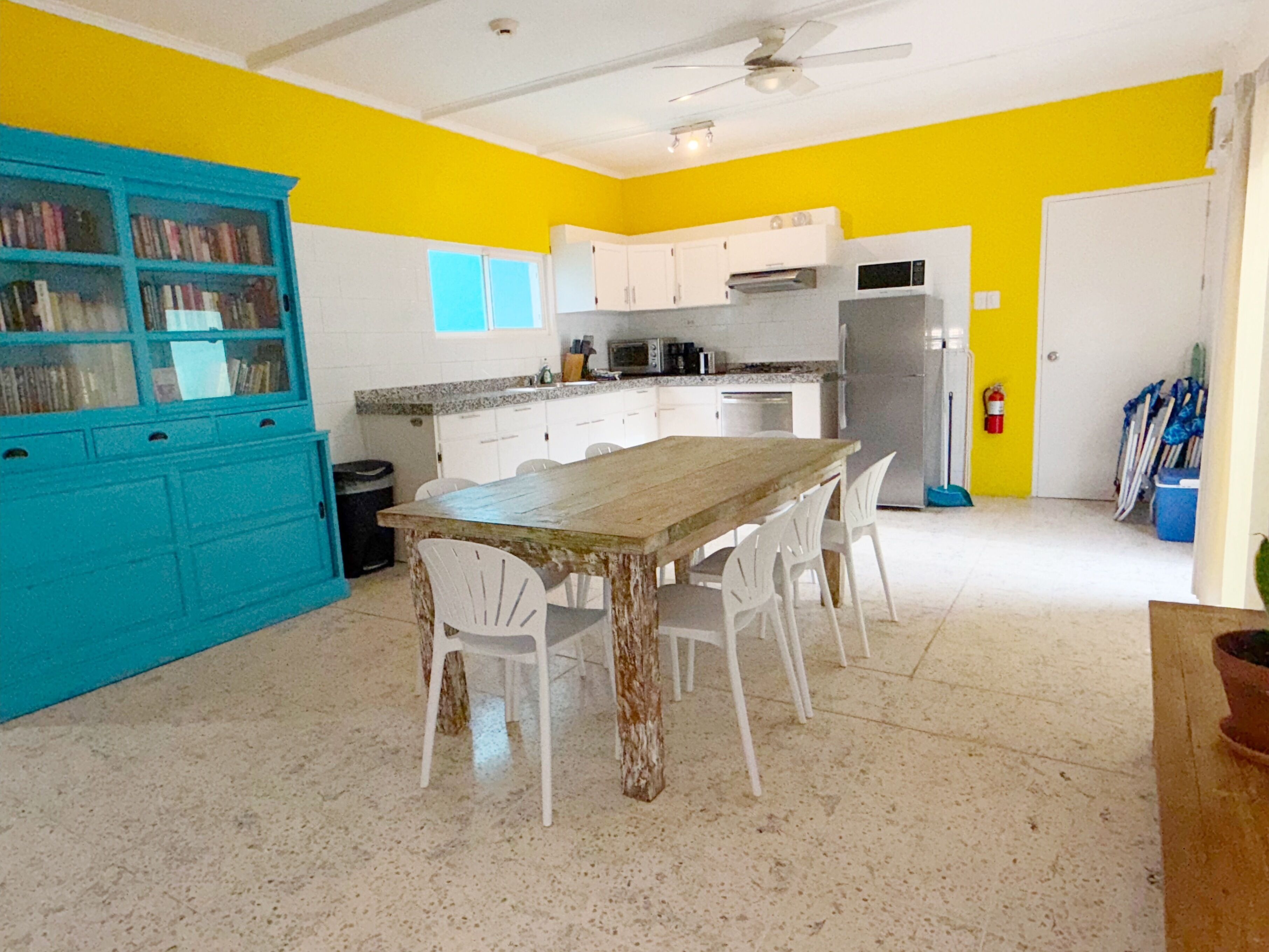A kitchen with white cabinets, a wooden table, and white chairs.