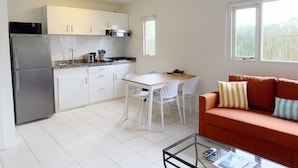 Un espacio habitable compacto con kitchenette, comedor y zona de estar con sofá.