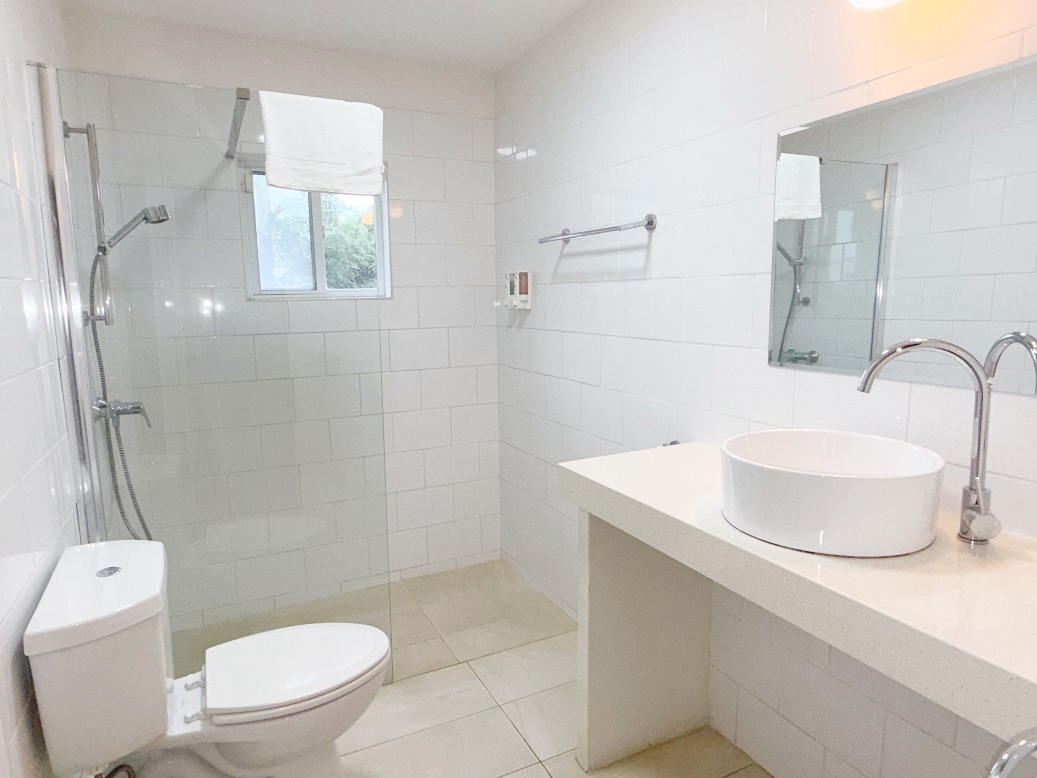 Une salle de bain équipée de toilettes, d’un lavabo, d’un miroir et d’une douche.