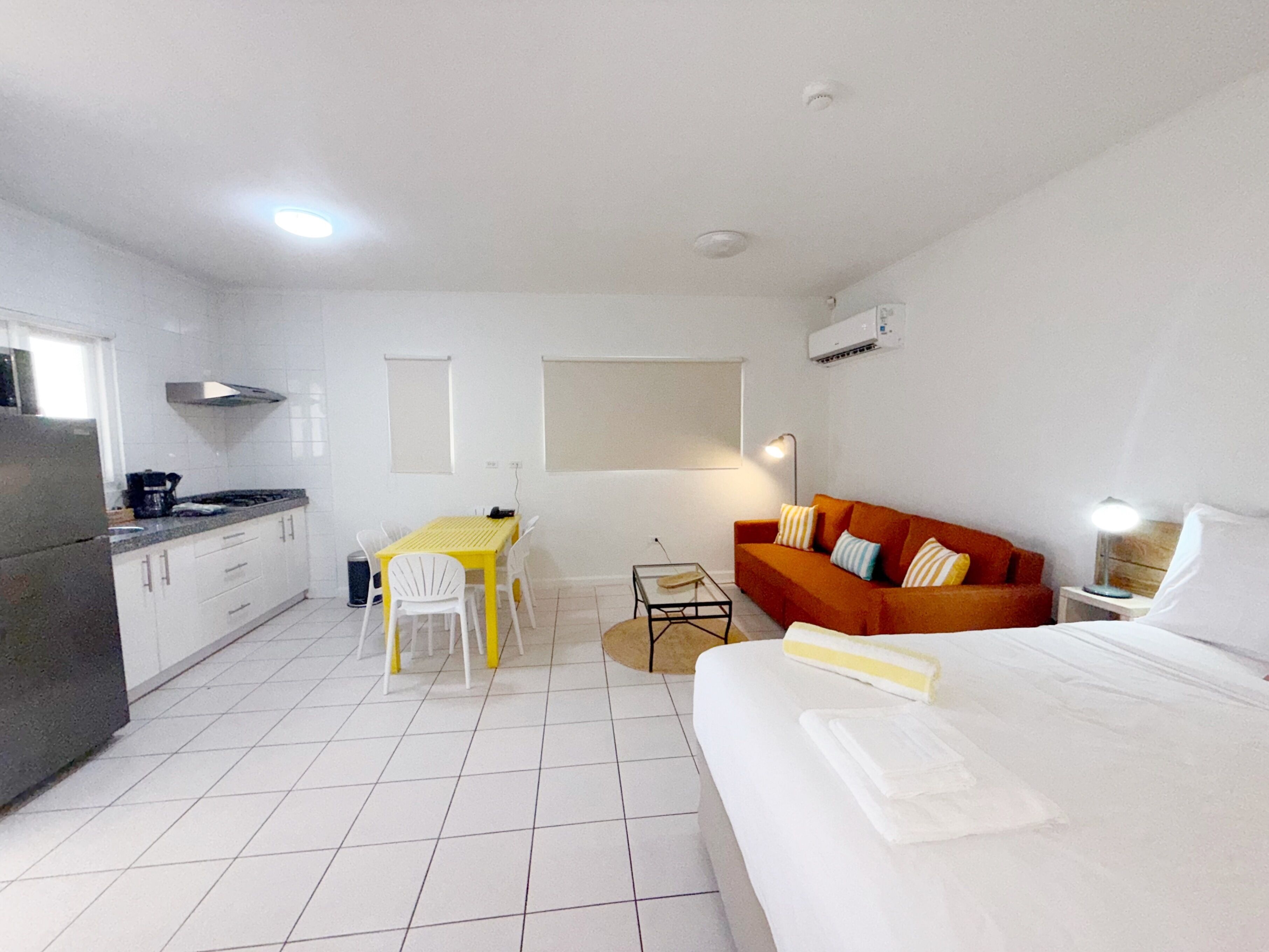 Una habitación de hotel compacta con kitchenette, una mesa de comedor, un sofá y una cama.