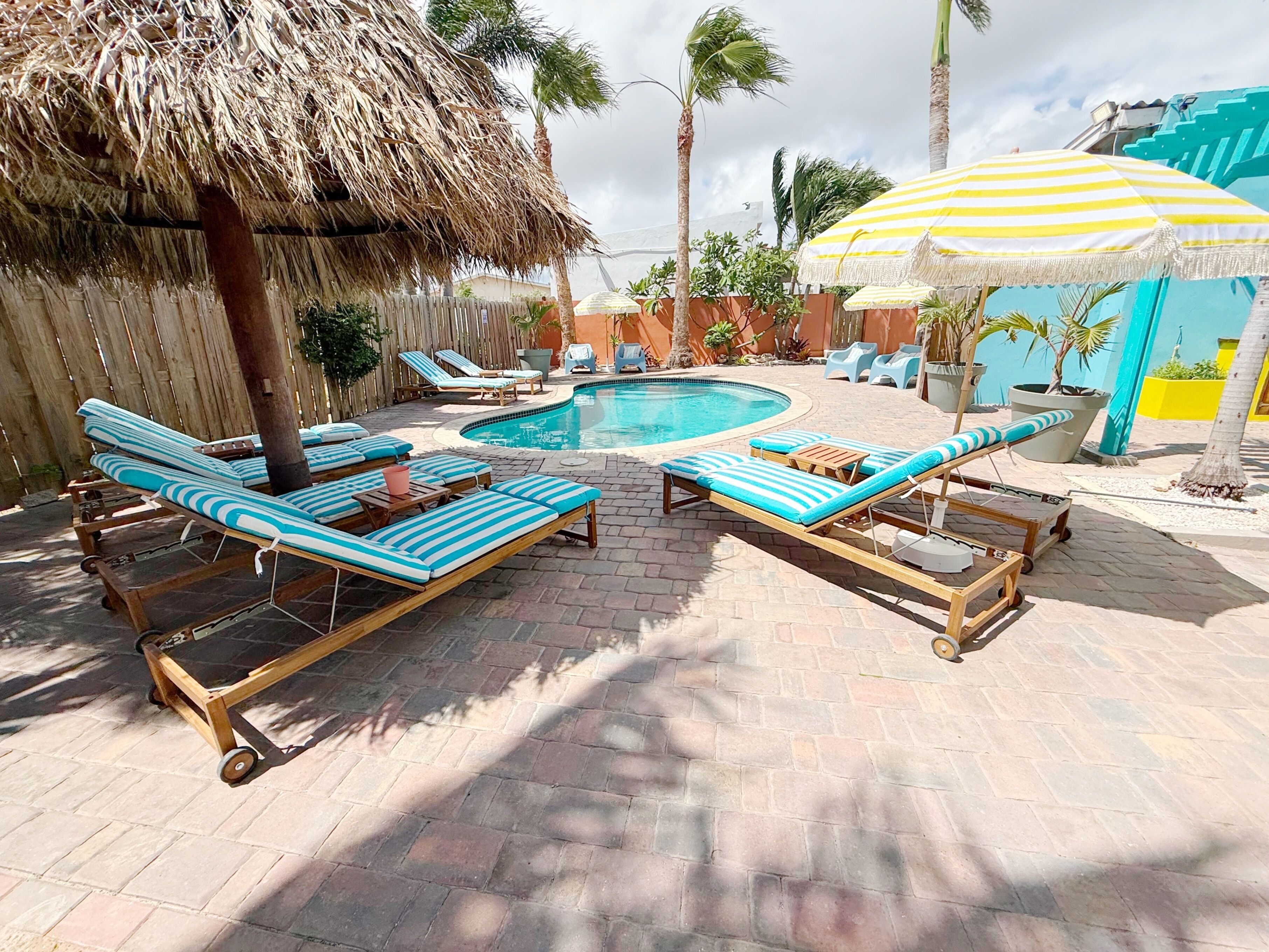 A pool area with lounge chairs and a thatched umbrella.