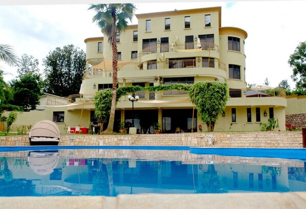 A multi-story hotel with a pool in the foreground.