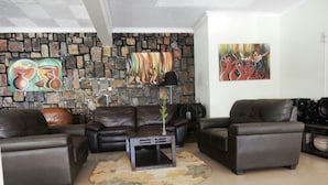 Een woonkamer met leren banken, een stenen muur en kunstwerken.