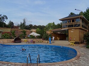 A swimming pool with a lifeguard tower, lounge chairs, and a covered seating area.