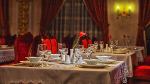 A dining table set with white plates, glasses, and a vase with a red rose. - Emirhan (Samarkand)