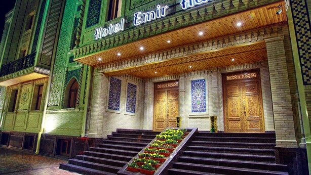 A hotel entrance with a grand staircase, ornate doors, and a sign reading "Hotel Emir Han". - Emirhan (Samarkand)