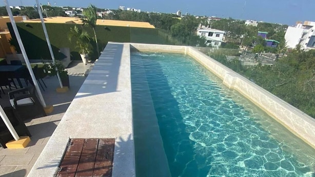 A rectangular swimming pool with clear water, surrounded by a concrete deck.