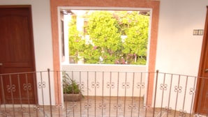 A multi-level interior with a central courtyard, featuring a stone floor, metal railings, and wooden doors.