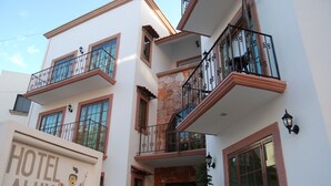 A multi-story hotel with balconies, stone accents, and a sign reading "HOTEL ALUX (ALUSH)".