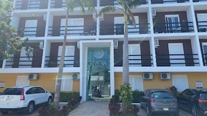 A multi-story hotel with a modern design, featuring balconies and air conditioning units.