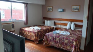 A hotel room with two beds, a television, and a window with a view of a red building outside. - Hotel Alux Cancun (Cancun)