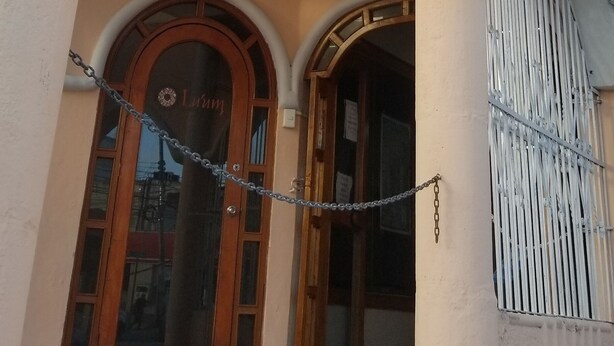 A hotel entrance with a distinctive archway labeled "HOTEL ALUX" and a chain-link security fence. - Hotel Alux Cancun (Cancun)